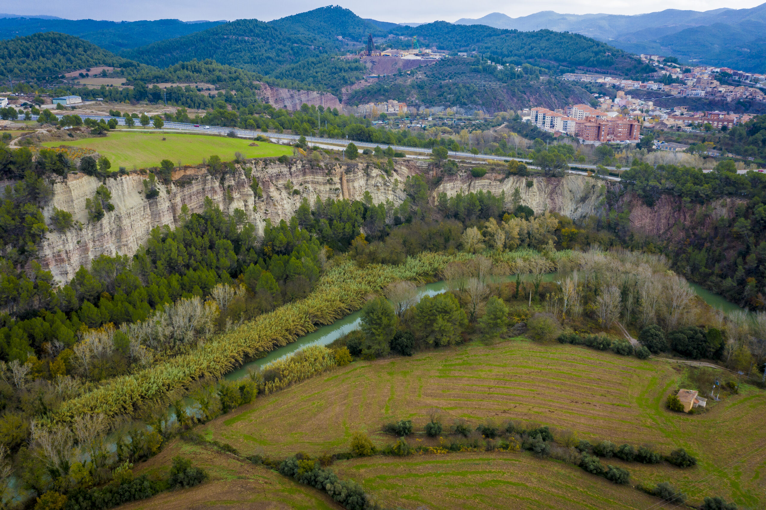 Vista del paisatge natural que envolta Súria amb el riu Cardener serpentejant entre camps i vegetació.
