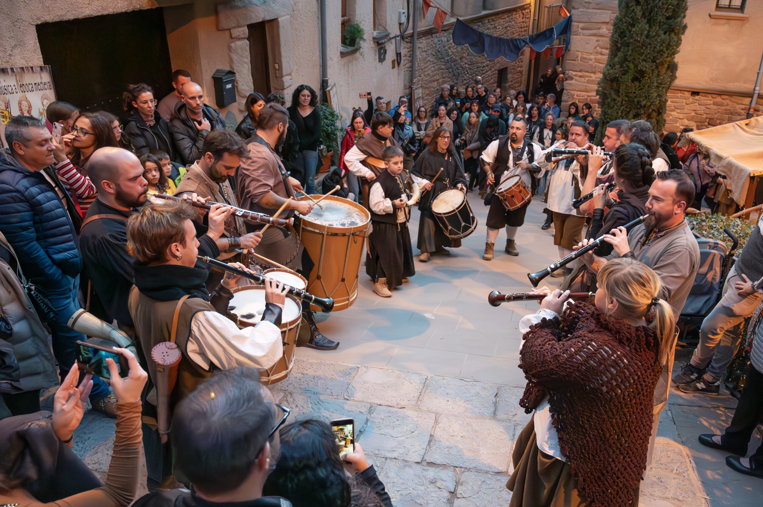 Súria Fira Medieval del Poble Vell, uns músics d'estil medieval toquen al carrer Major envoltats de visitants.